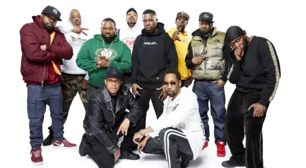 Grupa Wu-Tang Clan członkowie pozuje do zdjęcia. Wszyscy ubrani są w charakterystyczne dla hip-hopu stroje.