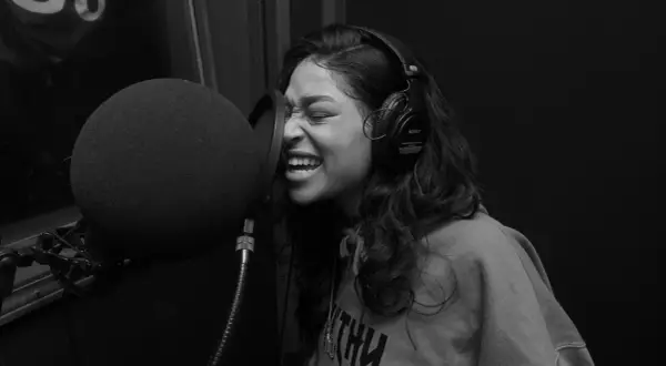 Kobieta w słuchawkach nagrywa rap i trap w studiu.