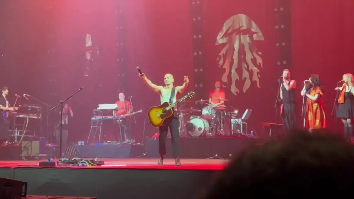 Krzysztof Zalewski koncert: wokalista z gitarą na scenie, zespół gra, tłum szaleje.