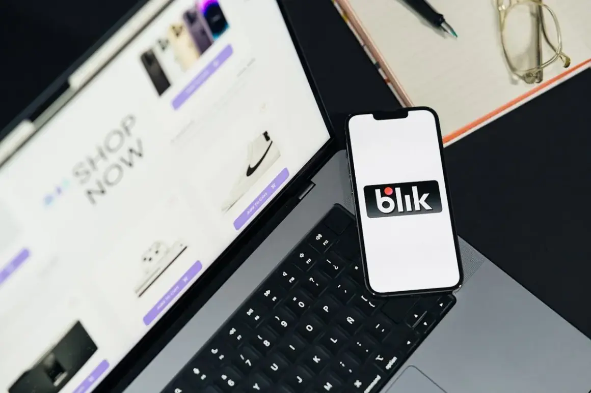 Telefon z logo Blik obok laptopa z otwartym sklepem internetowym. Szybkie zakupy z Blik!