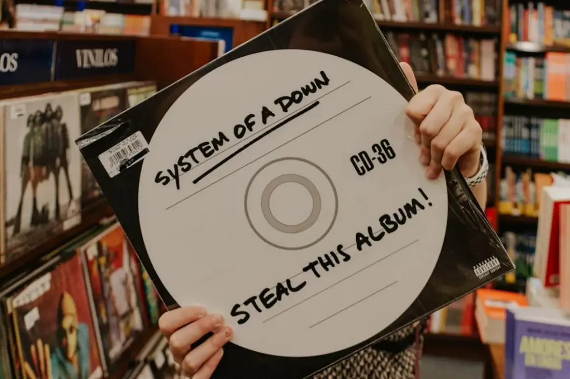 Ręce trzymają okładkę płyty System of a Down "Steal This Album!". Wybór między winyl czy CD jest tu oczywisty.