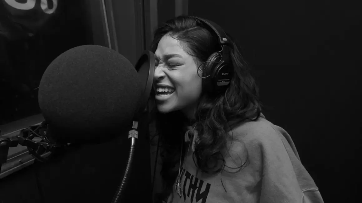 Kobieta w słuchawkach nagrywa rap i trap w studiu.