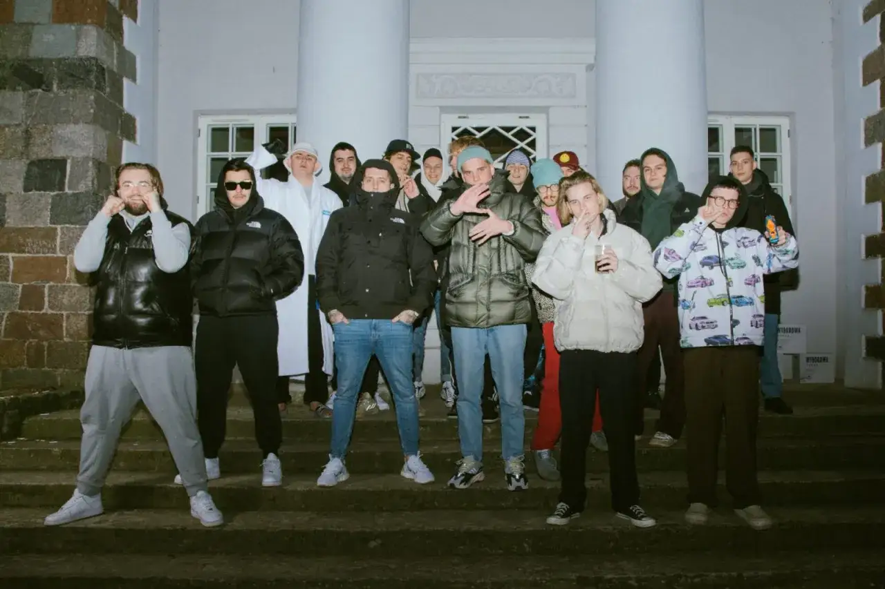 Grupa młodych ludzi, kt&oacute;rzy są w SBM, pozuje na schodach przed budynkiem.