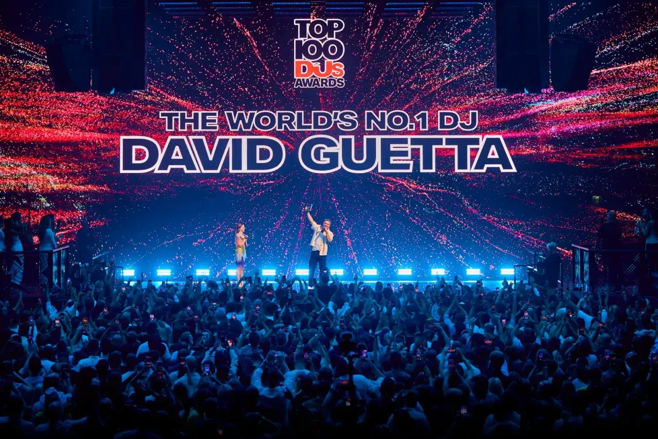 David Guetta, jeden z najbardziej znanych DJ-&oacute;w, odbiera nagrodę na scenie przed tłumem fan&oacute;w.