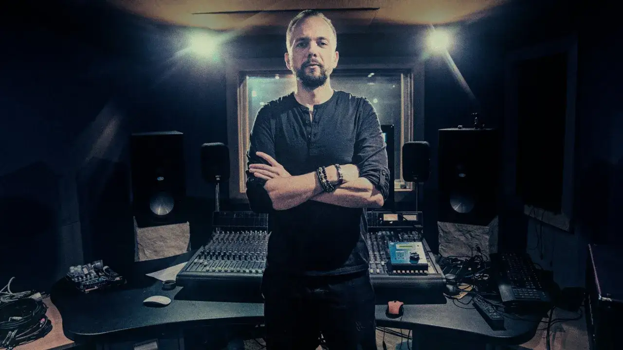Artysta w studiu nagraniowym, gotowy na hot 16 challenge. Wokół konsoleta, monitory i sprzęt.