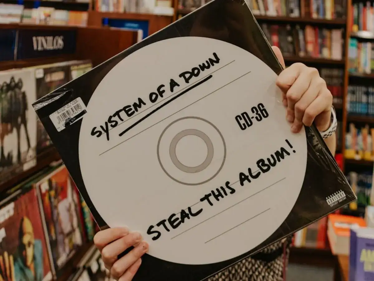Ręce trzymają okładkę płyty System of a Down 