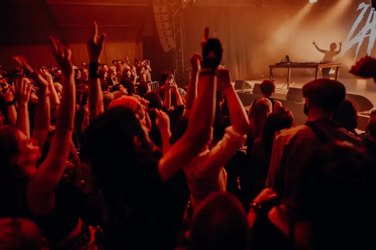 Tłum szaleje na koncercie, ręce w górze, światła sceny oświetlają DJ-a. Natalia Zamilska w akcji, tworzy niezapomnianą atmosferę.