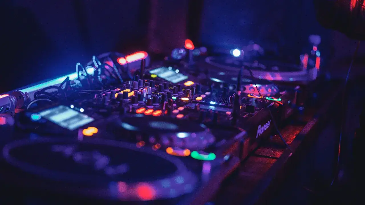 Światła klubu pulsują w rytm muzyki. Na pierwszym planie widać sprzęt techno djs, gotowy do stworzenia niezapomnianej nocy.