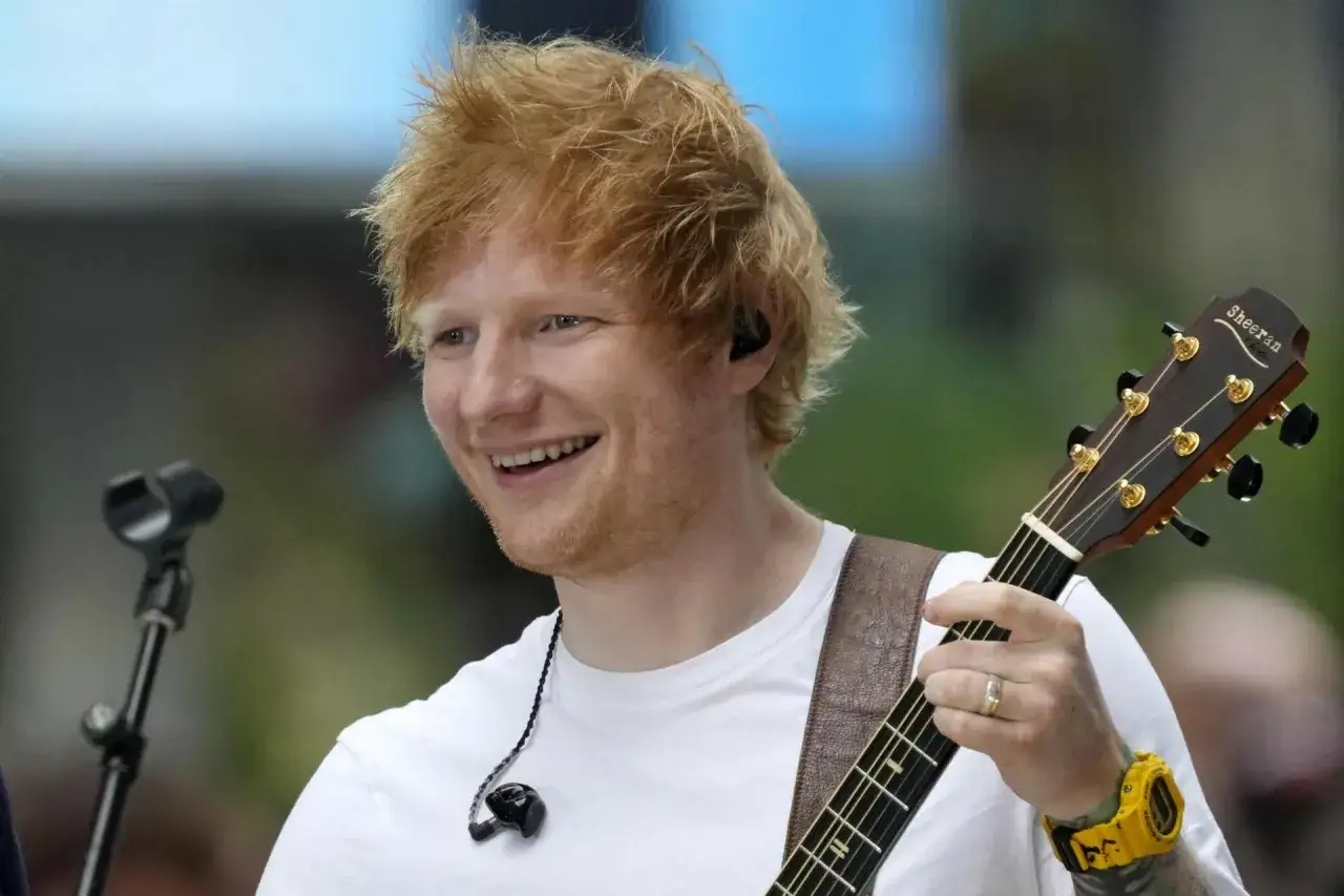 Ed Sheeran w Polsce, uśmiechnięty, gra na gitarze.