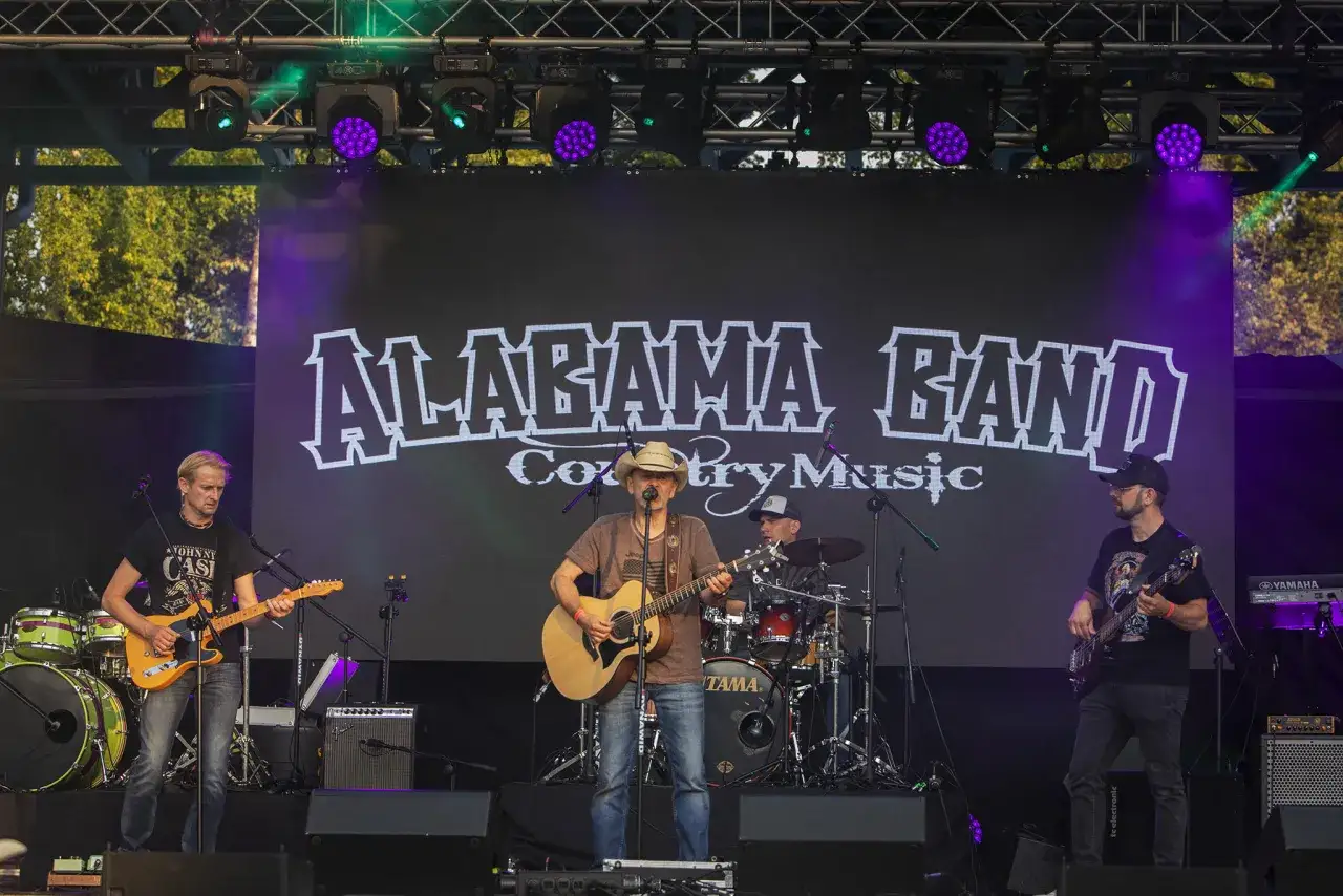 Zespół Alabama Band gra muzykę country na żywo. Gwiazdy country w akcji, światła sceniczne i publiczność w tle.