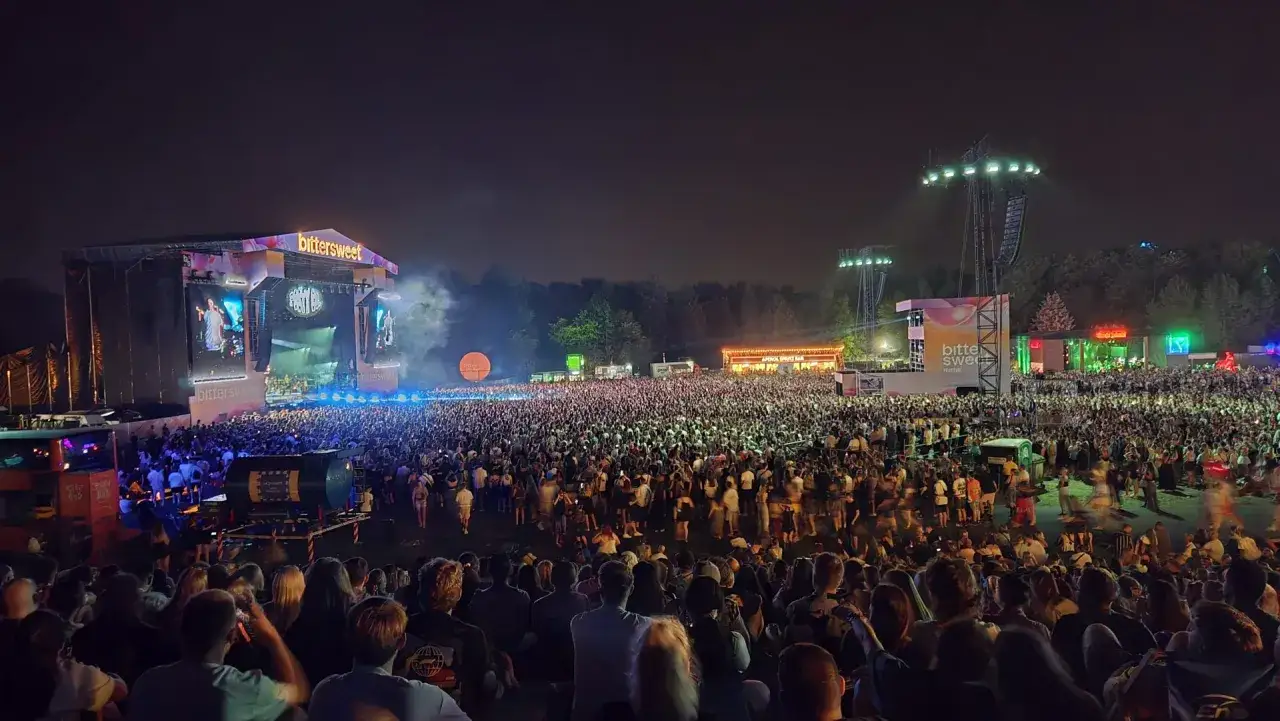 Tłum ludzi na nocnym koncercie, światła sceny i baner