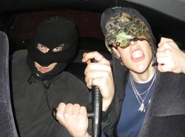 Dwóch mężczyzn w kominiarkach, jeden z nich trzyma tonfę, gotowi na bitwę w stylu tonfa rap.