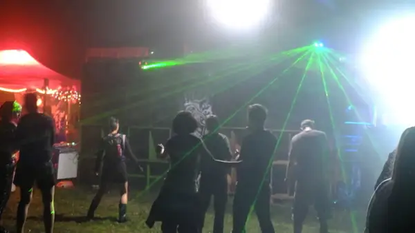 Nocna impreza z laserami, ludzie tańczą w rytm techno. Wykonawcy z lat 2000 tworzą niezapomnianą atmosferę.