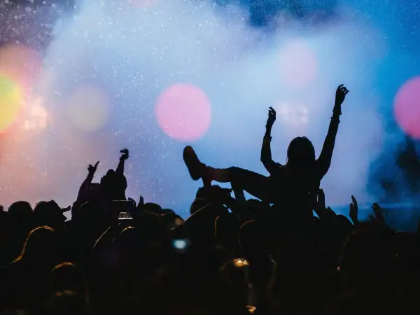 Tłumy na płock festiwal bawią się pod sceną. Jedna osoba niesiona jest na rękach, z ramionami uniesionymi w górę.