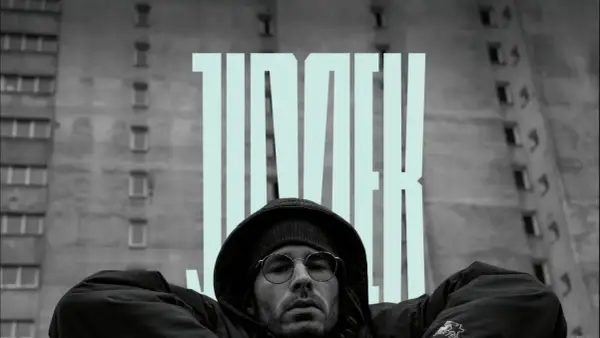 Mężczyzna w okularach i kapturze na tle bloku, z napisem "JIMEK". To część historii polskiego hip hopu.
