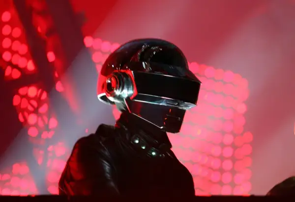 Thomas Bangalter w ikonicznym hełmie Daft Punk, na tle czerwonych świateł scenicznych.
