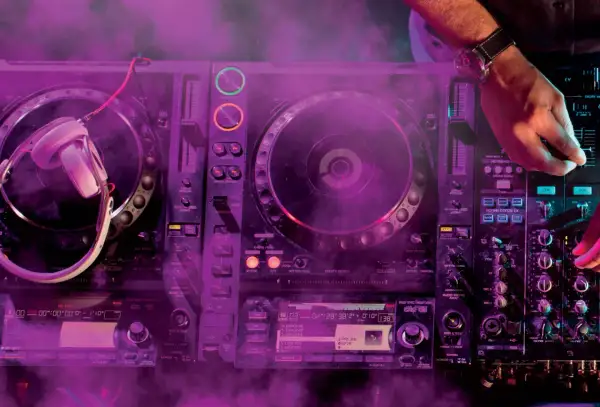 DJ gra na konsoli z fioletowym dymem.