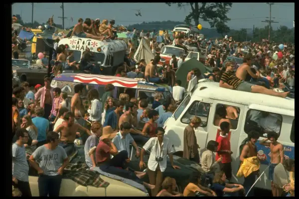 Tłum ludzi na festiwalu, siedzący na dachach vanów i samochodów. To właśnie woodstock co to za wydarzenie?