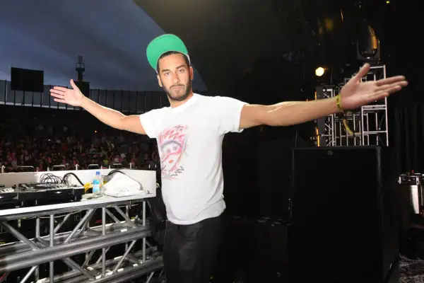 Armand Van Helden wita tłum na koncercie, rozkładając ramiona.