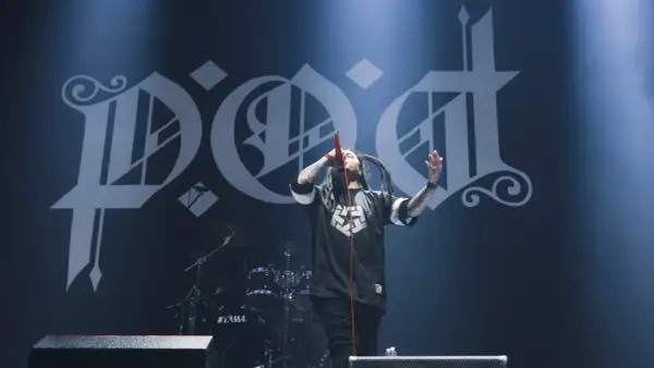 Sonny Sandoval z P.O.D. śpiewa na scenie, z charakterystycznym logo zespołu w tle.