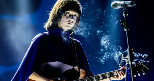 Artystka z błyszczącymi łzami na twarzy gra na gitarze podczas MTV Unplugged Polska. Dym unosi się wokół niej.