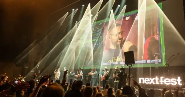 Zespół na scenie podczas koncertu na Next Fest. W tle wielki ekran z transmisją i światła.